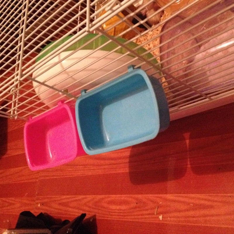 Deux gamelles à clipser, rose et bleue, fixées côte à côte sur les barreaux d'une cage
