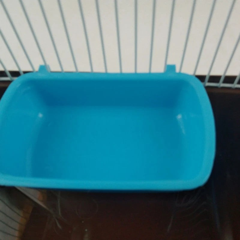 Gamelle bleue clipsée à l'intérieur d'une cage, vue depuis les barreaux